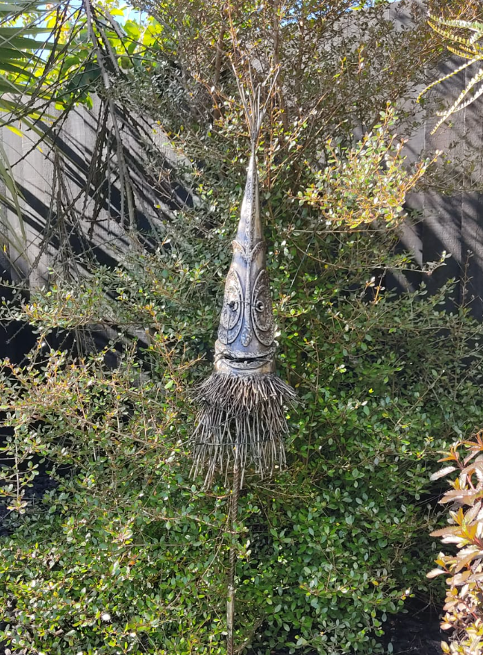 Decorative dukduk with face-like design hanging from a tree